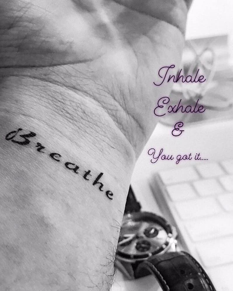 Wrist tattoo reading "Breathe"