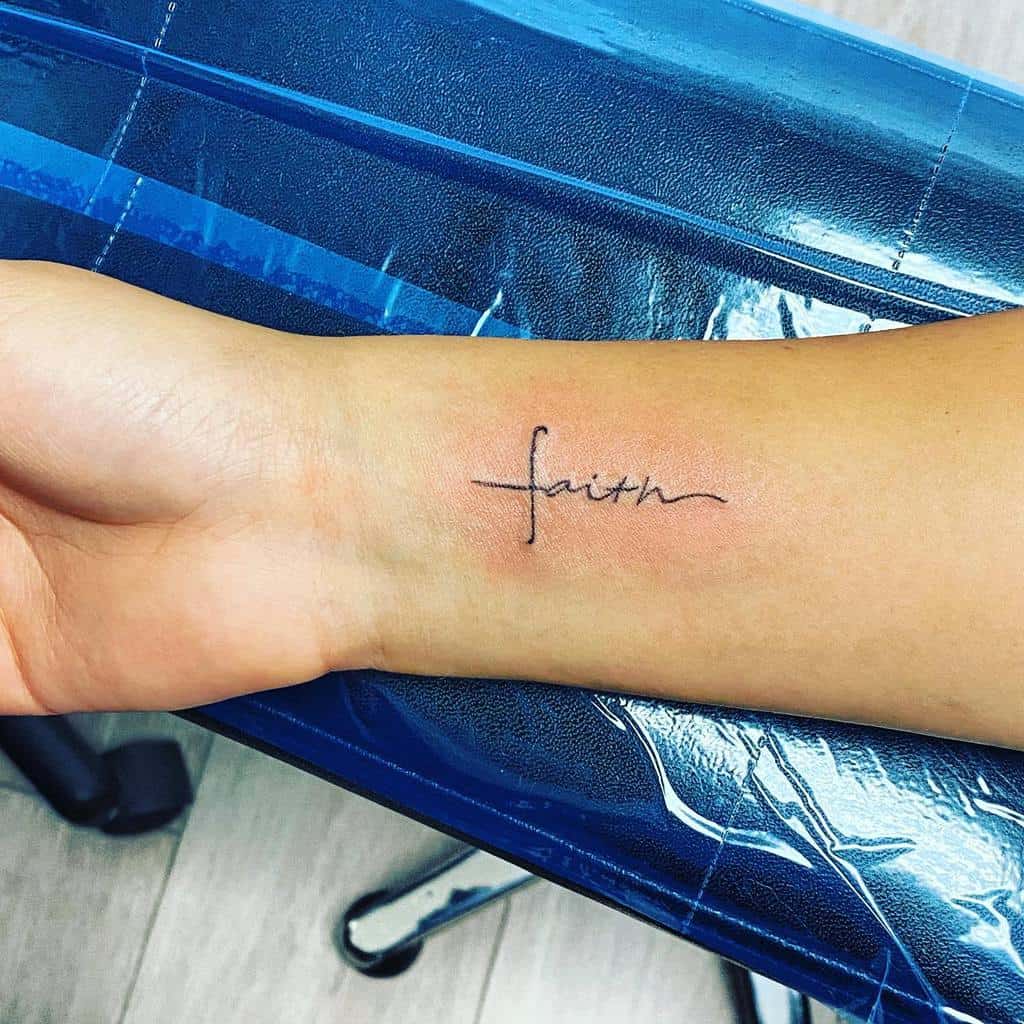 A subtle tattoo on the wrist spells "faith," with the elegant twist that the "f" gracefully transforms into a cross