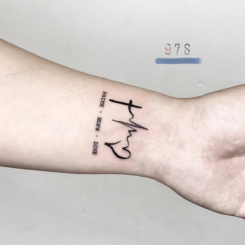 Wrist tattoo shows heartbeat line with cross, heart, and text "FAITH HOPE LOVE"