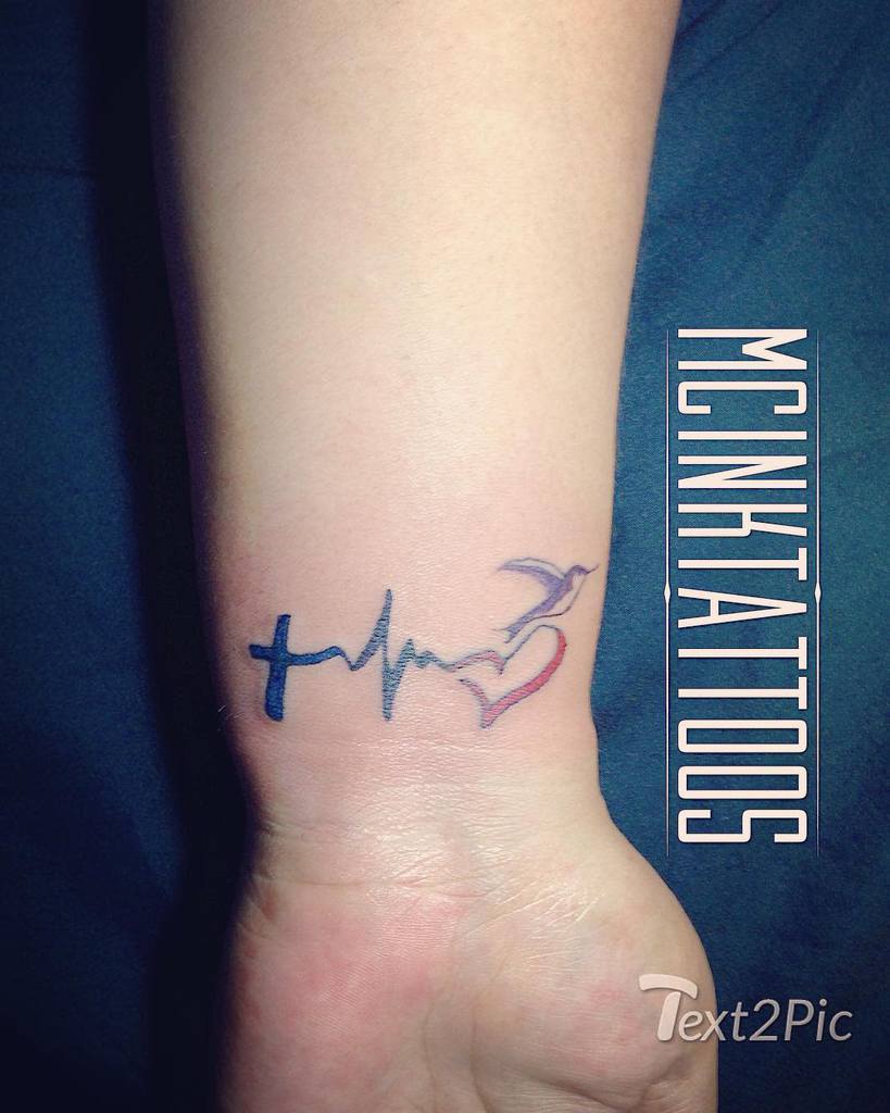 Wrist tattoo of a cross, heartbeat line, heart, and bird in flight