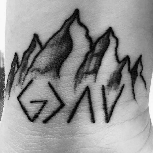 Wrist tattoo featuring "God is greater than the highs and lows" symbol with detailed shaded mountain peaks