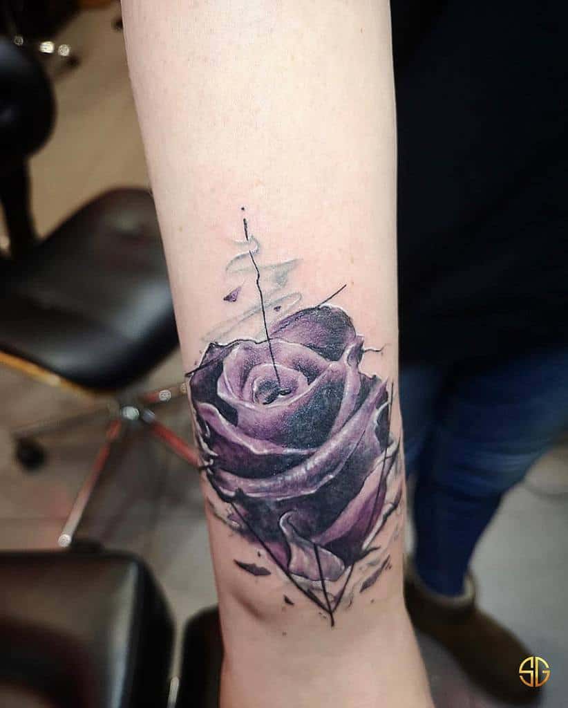 A detailed tattoo of a purple rose with cracks and delicate lines, featuring a subtle, artistic design, placed on the forearm
