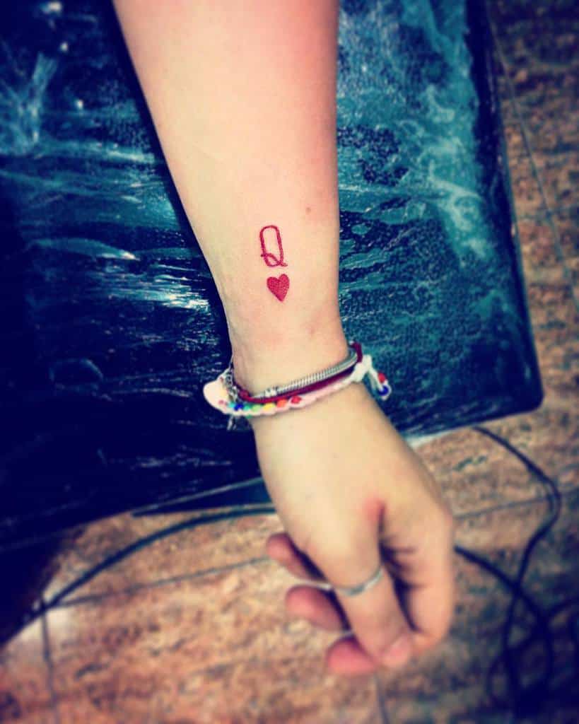 A wrist with a "Q" and heart tattoo