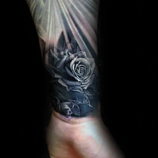 Black and gray rose tattoo with skulls on a forearm
