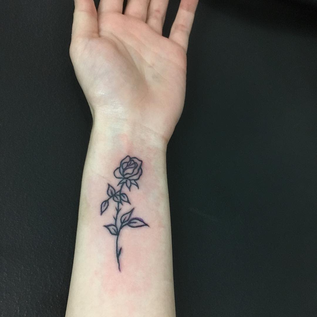 Outline tattoo of a rose on a wrist