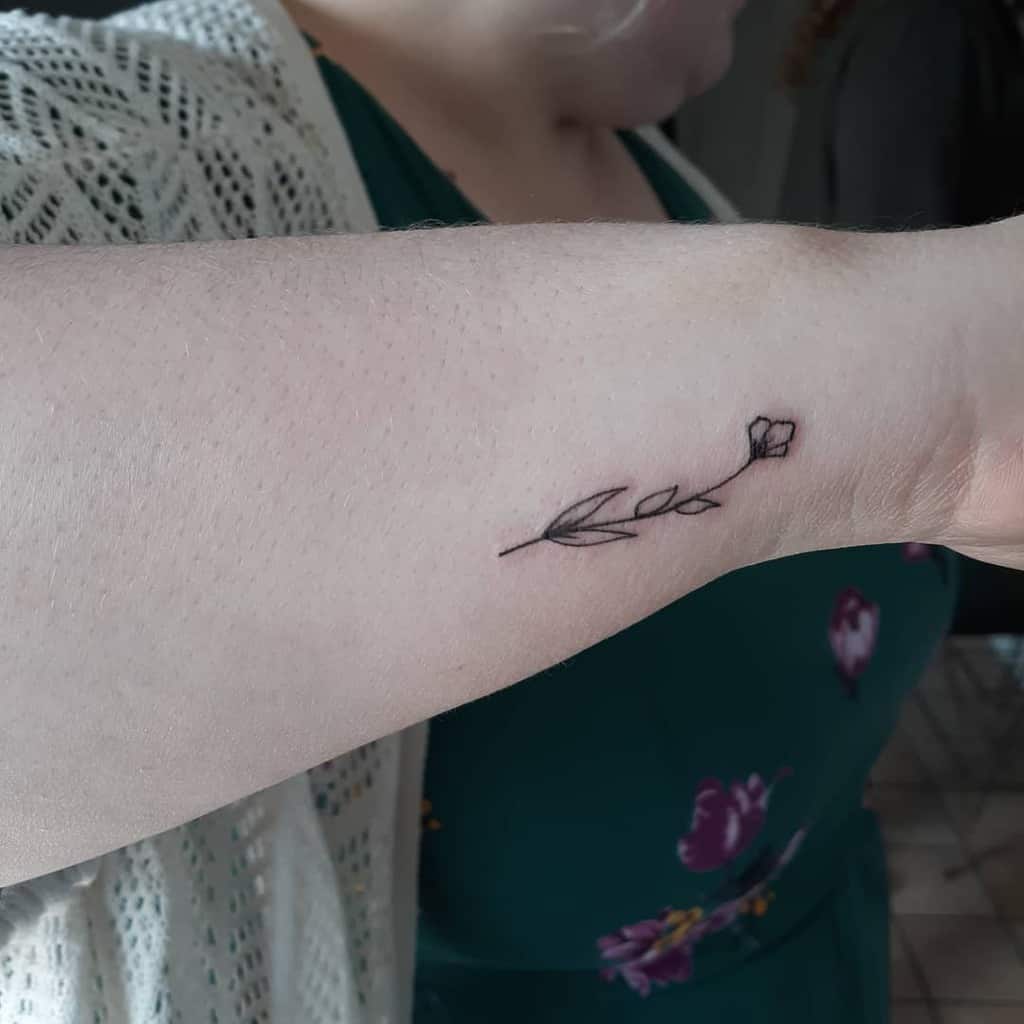 A delicate line drawing tattoo of a flower on an arm