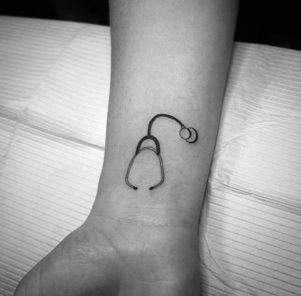 Minimalist stethoscope tattoo on the wrist, symbolizing a deep commitment to the medical profession and a passion for patient care.