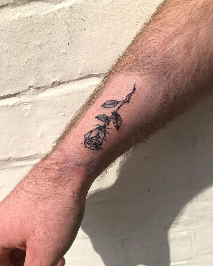 Wrist with a detailed black rose tattoo