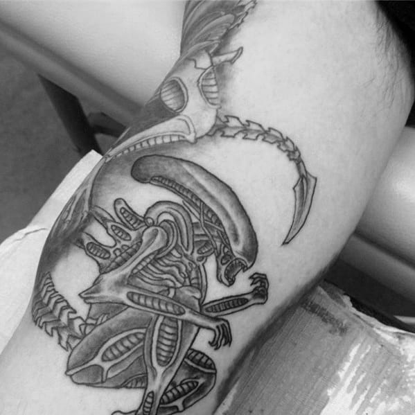 Black and grey Xenomorph tattoo with clean linework, showing the alien in a crouched pose with a detailed tail and exoskeleton.