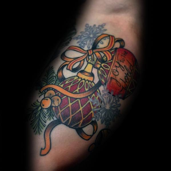 Christmas tattoo of elegant vintage ornaments with gold ribbon, pine branches, and snowflakes, featuring a festive message reading "Joy to the World."