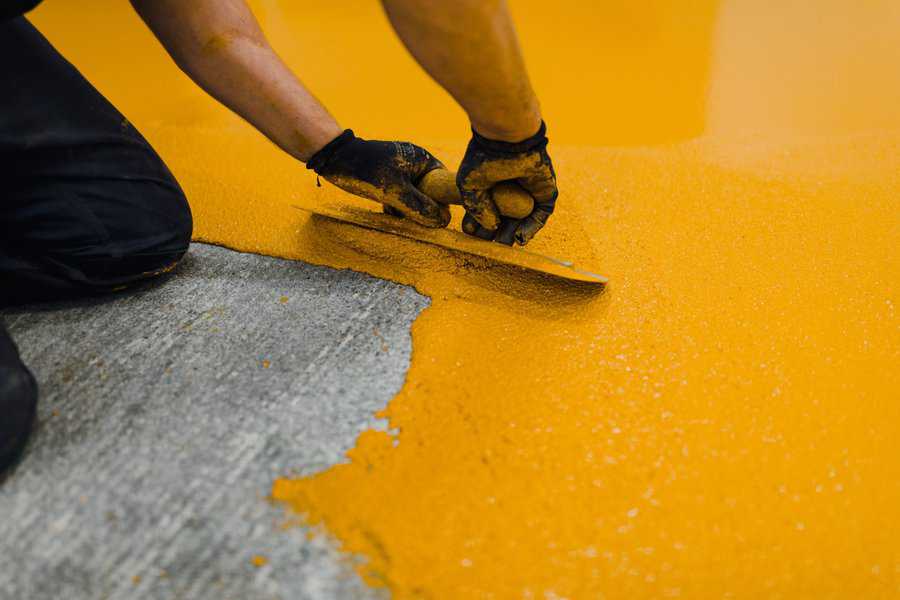 ellow epoxy floor coating being spread smoothly on a concrete surface.