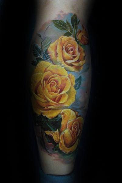 Tattoo of vibrant yellow roses with green leaves on skin