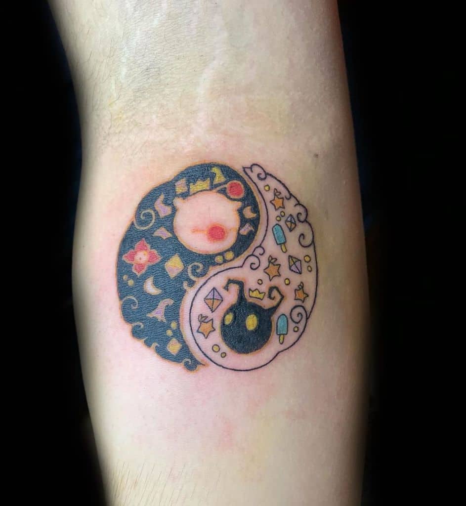 Kingdom Hearts-inspired yin-yang tattoo featuring a Moogle and Heartless symbol, decorated with stars, Keyblade charms, and mystical patterns.