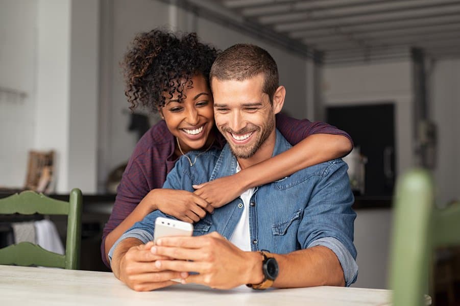 young couple embracing while looking at smartphone