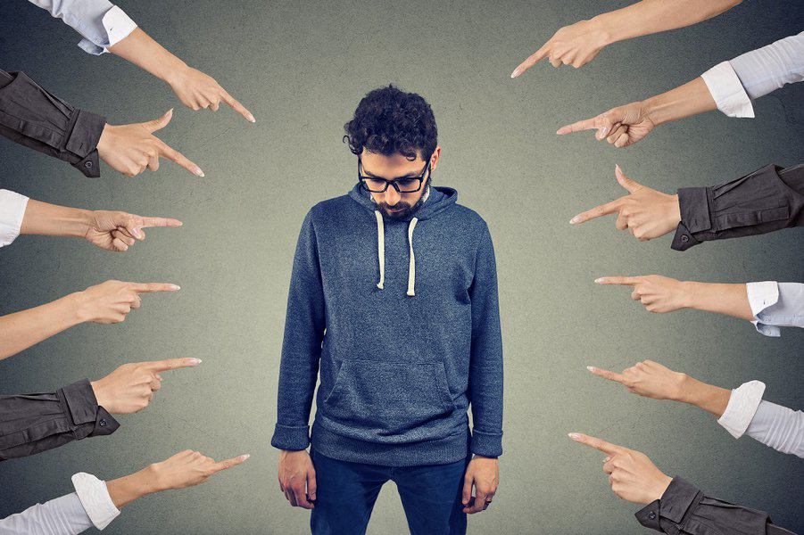young man feeling guilty while fingers pointing at him concept