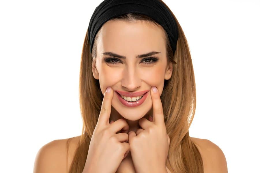 young woman stretching mouth in fake smile with her fingers 