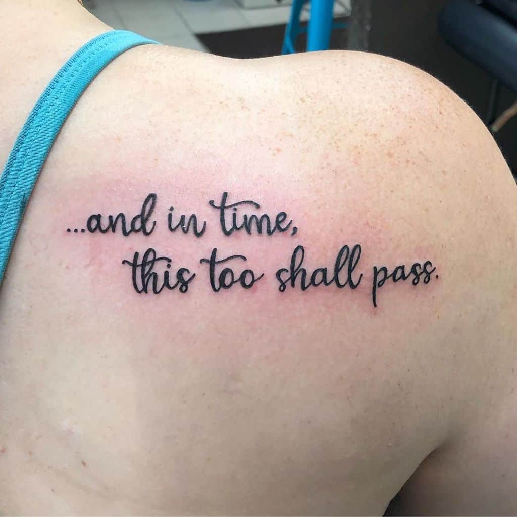 A tattoo on the shoulder reading, "...and in time, this too shall pass" in a cursive font.