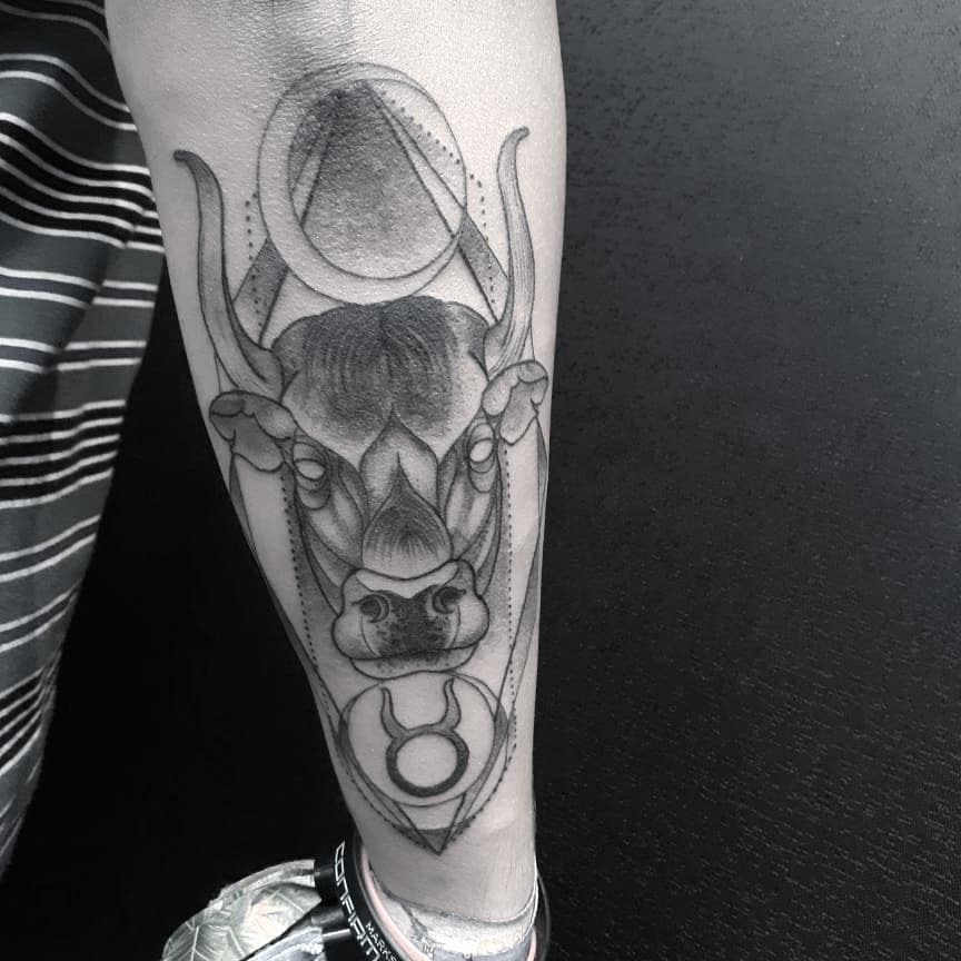 Forearm tattoo of a bull with geometric elements and a Taurus symbol, combining realism with modern linework for a bold, powerful design.